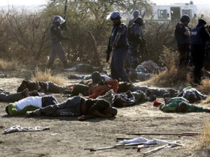 A policeman gestures in front of some of the dead miners after they were shot outside a South African mine in Rustenburg